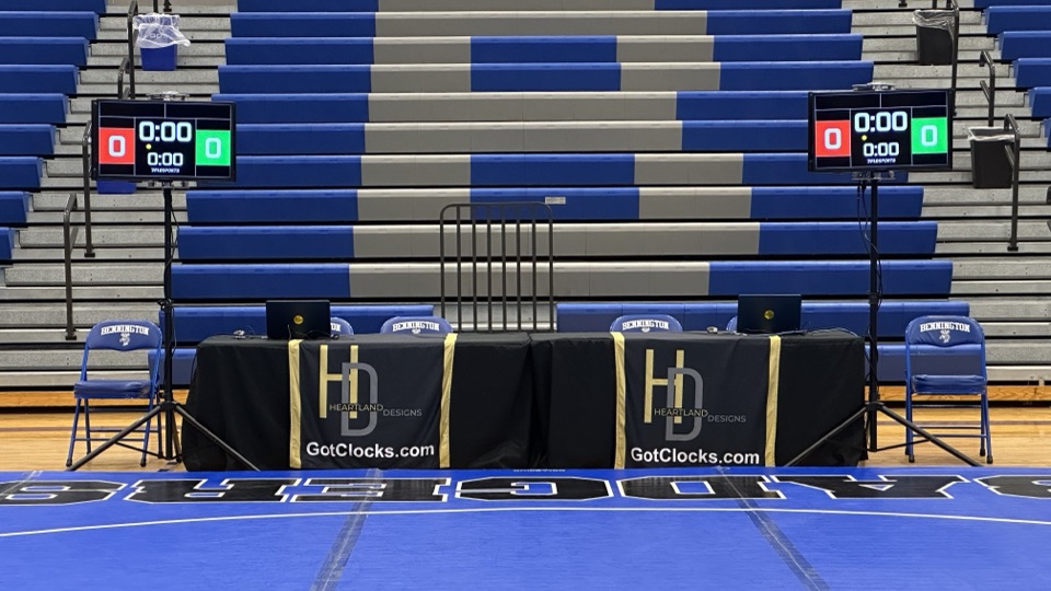 Twin Got Clocks scoreboard displays and branded table drapes at a high-school wrestling dual